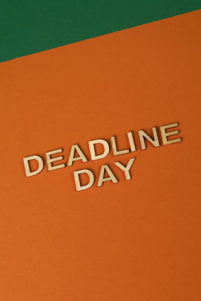 Vertical shot of 'Deadline Day' in wooden letters on an orange paper background.