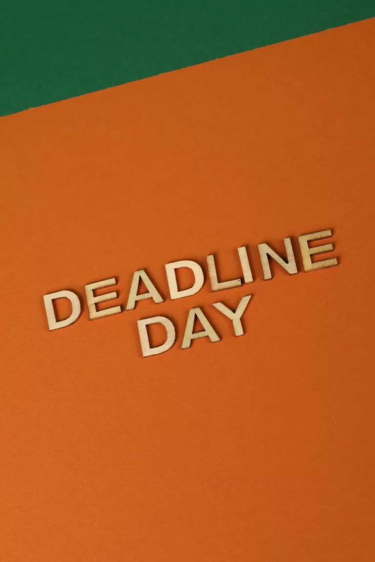 Vertical shot of 'Deadline Day' in wooden letters on an orange paper background.