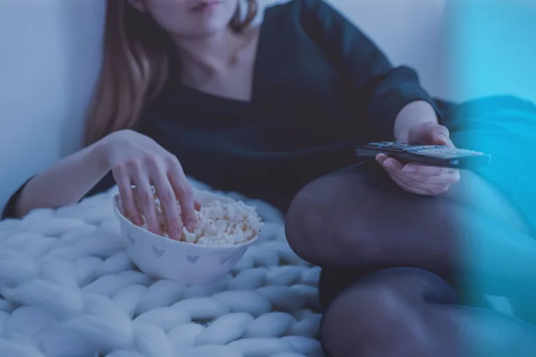 Cozy evening scene with woman enjoying popcorn and watching TV.